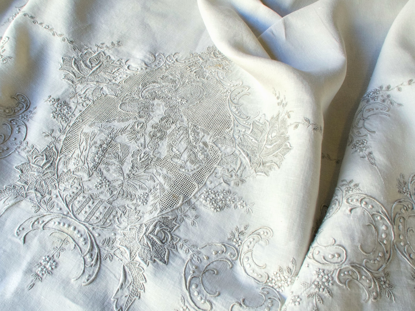 Appenzell tablecloth detail featuring embroidered lady framed by floral and scrolling border motifs