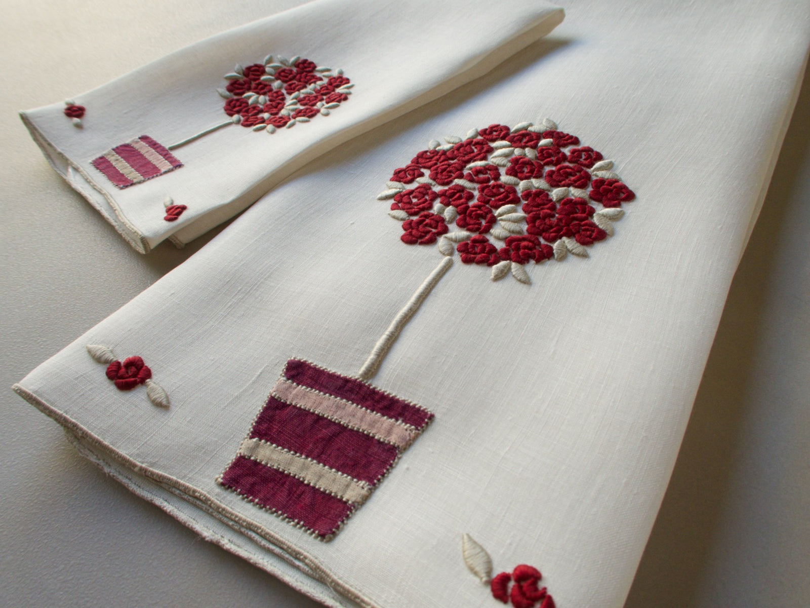 Marghab linen towels in the “Rose Tree” pattern, featuring a potted rose tree with maroon embroidered blossoms in a seldom-seen color — guest and fingertip sizes shown together.
