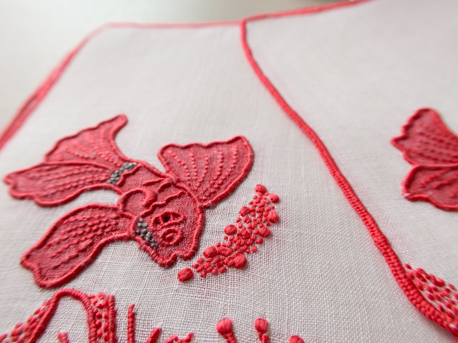 Detail of vintage Marghab Tropical Fish cocktail napkin showing extraordinary red embroidery and appliqué with coral and shell motifs