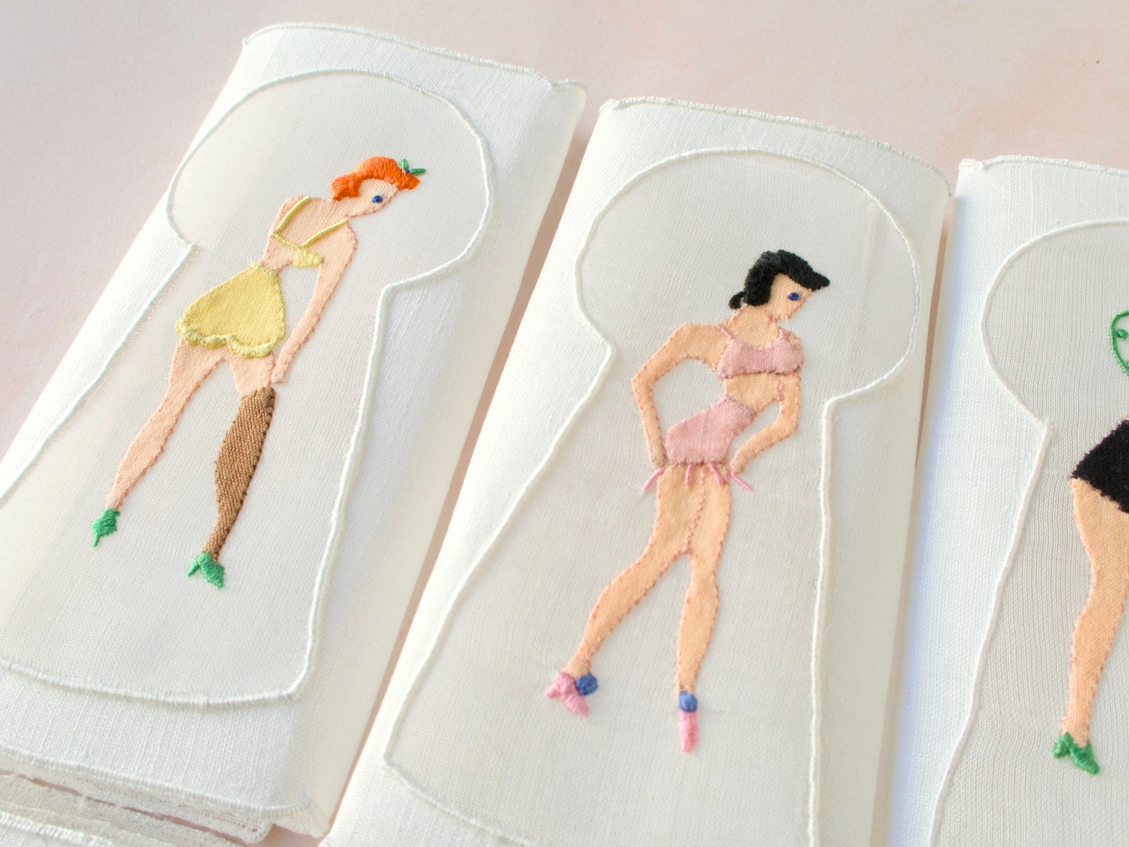 Detail of keyhole embroidery showing woman in pink lingerie, vintage Madeira linen cocktail napkin.