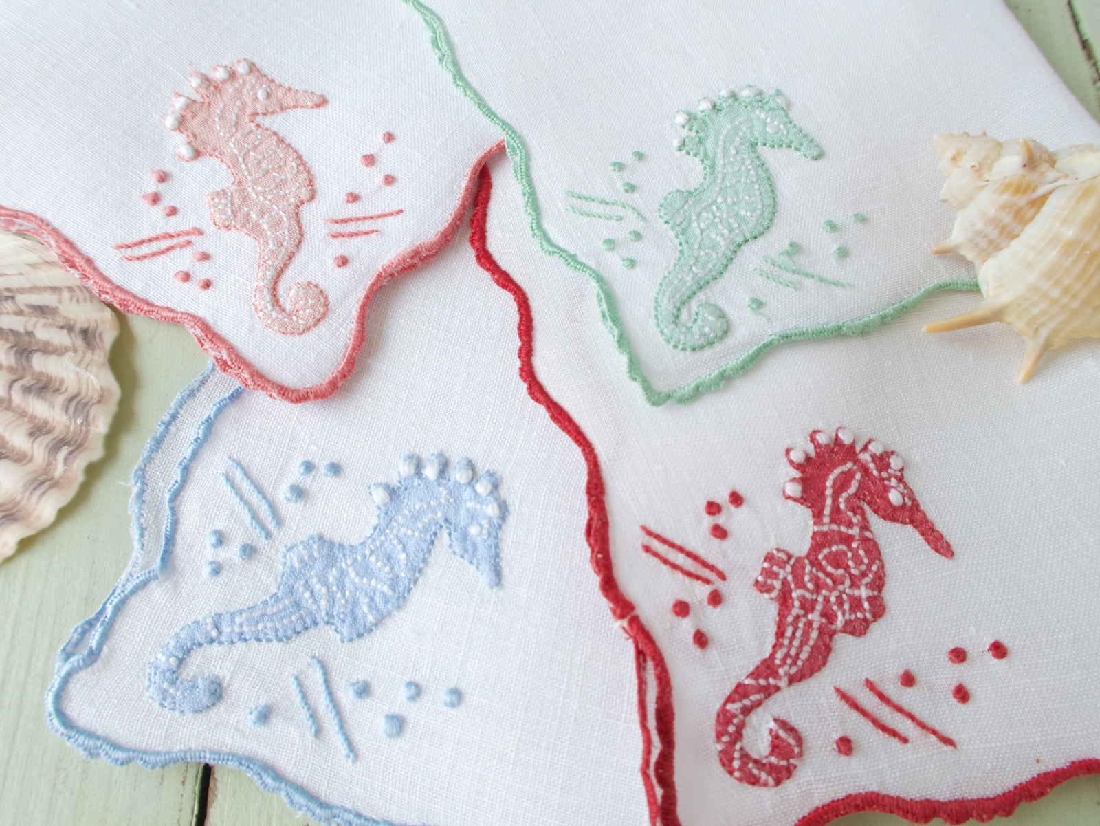 Vintage Madeira linen cocktail napkins with multicolor seahorse appliqué and embroidery, scalloped edges, set of 8 fanned on display.