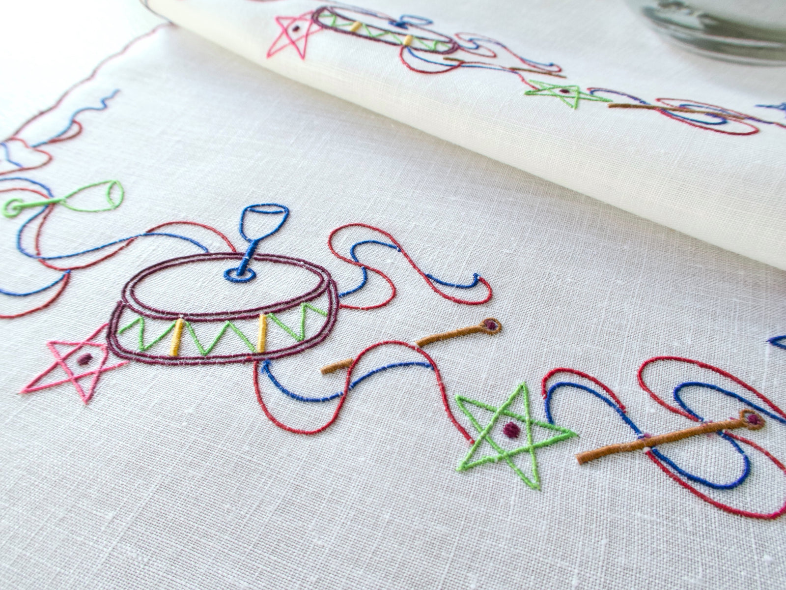 Vintage white linen cocktail napkins with colorful embroidered drums, stars & ribbons.