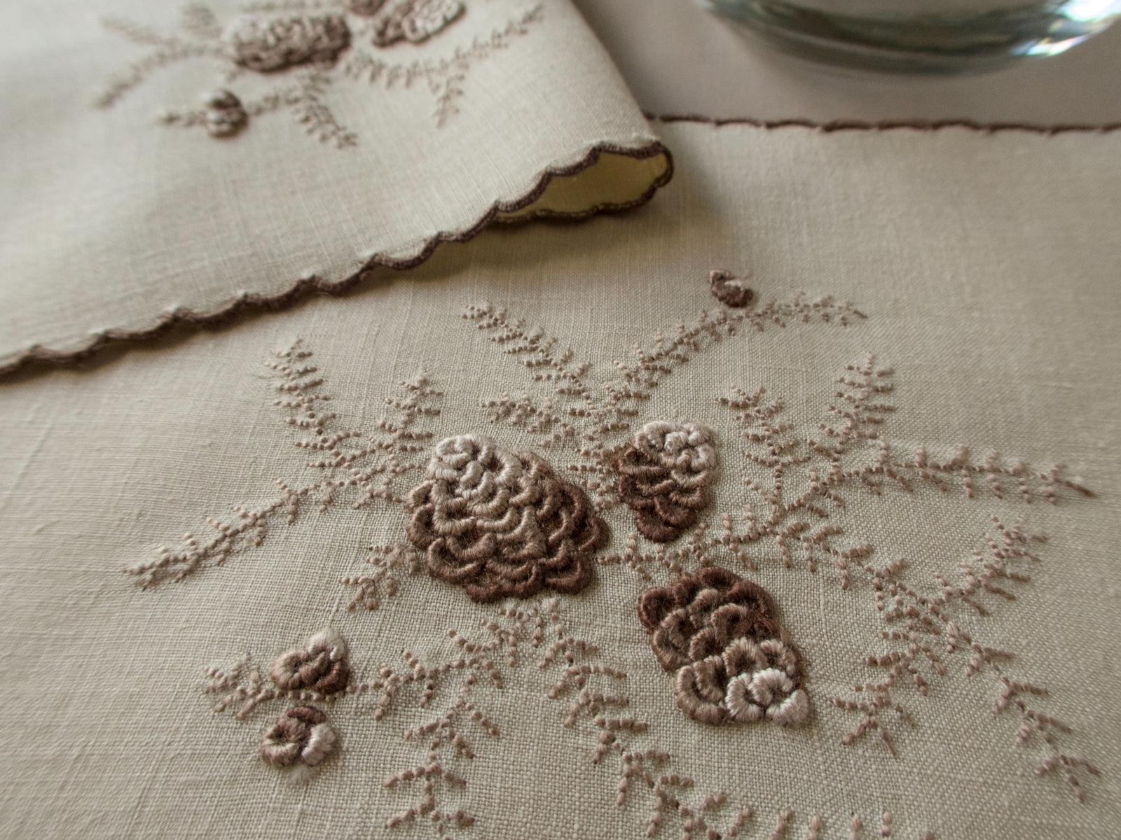 Close shot of Marghab's "Pines Cones" pattern, embroidery on linen cocktail napkin, Madeira handwork.