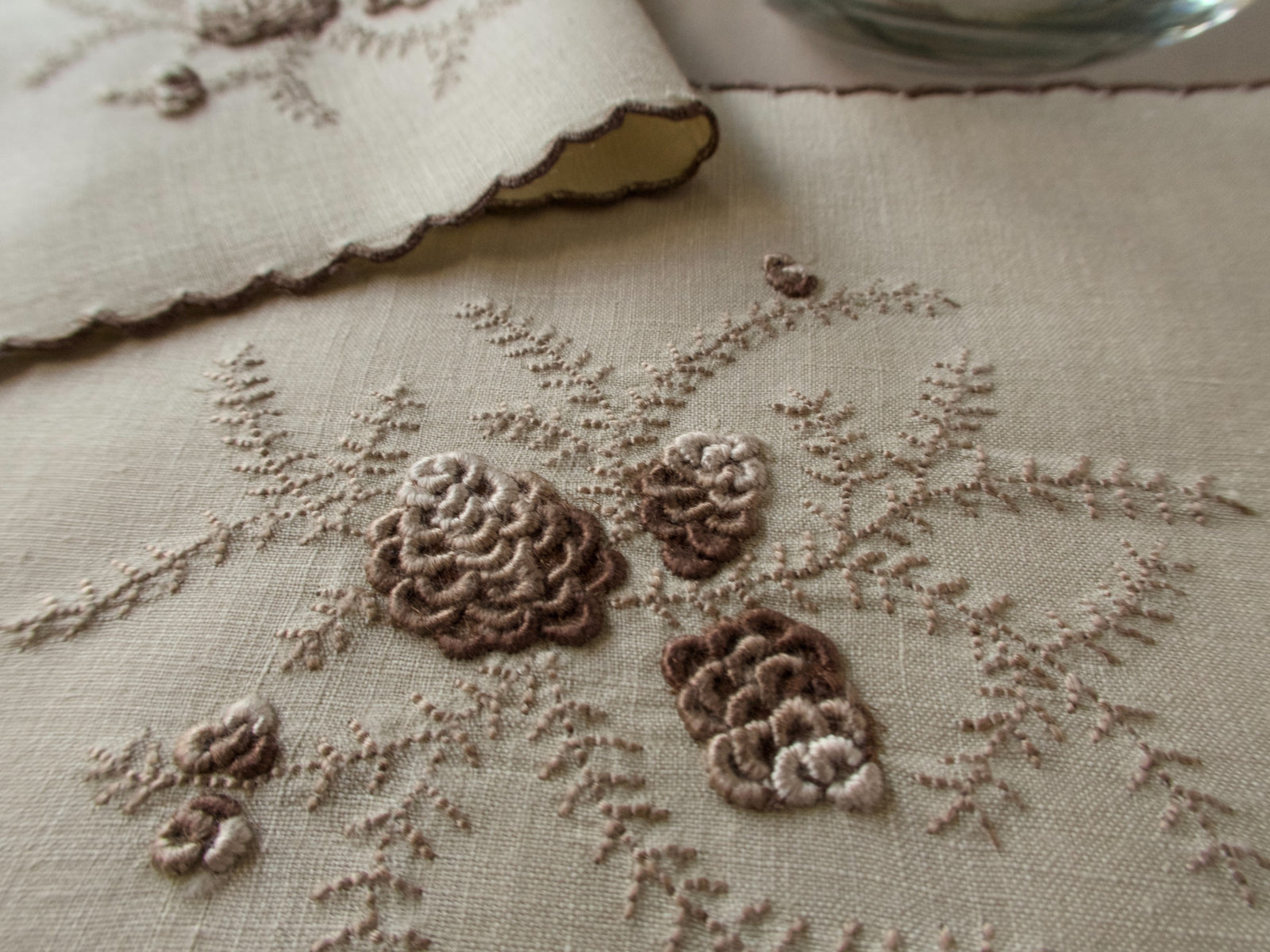 Close-up of raised brown pinecone embroidery on linen cocktail napkin, Marghab pattern, Madeira handwork.