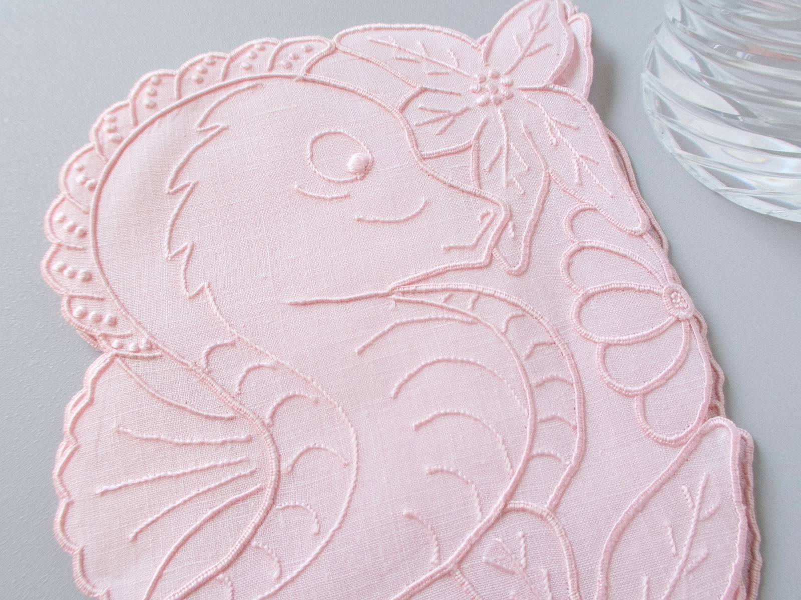 Close-up of vintage Madeira seahorse cocktail napkin showing fine pink linen and detailed hand embroidery