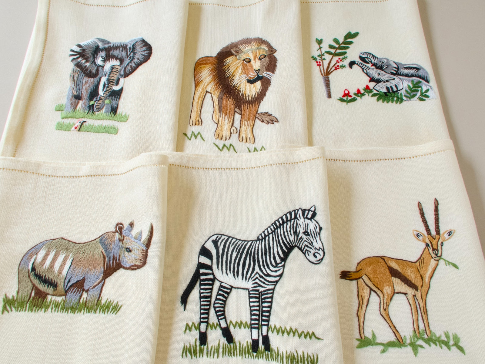 Six vintage hand embroidered safari placemats showing elephant, lion, rhino and zebra on linen with hemstitched border