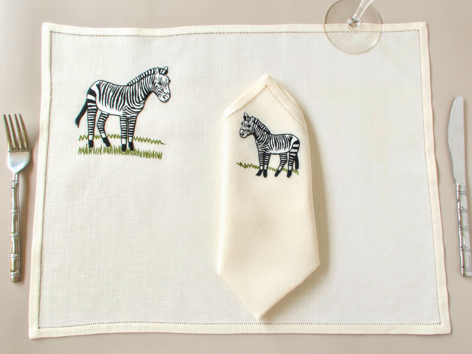 Vintage hand embroidered placemat and folded napkin showing zebra design and hemstitched border detail