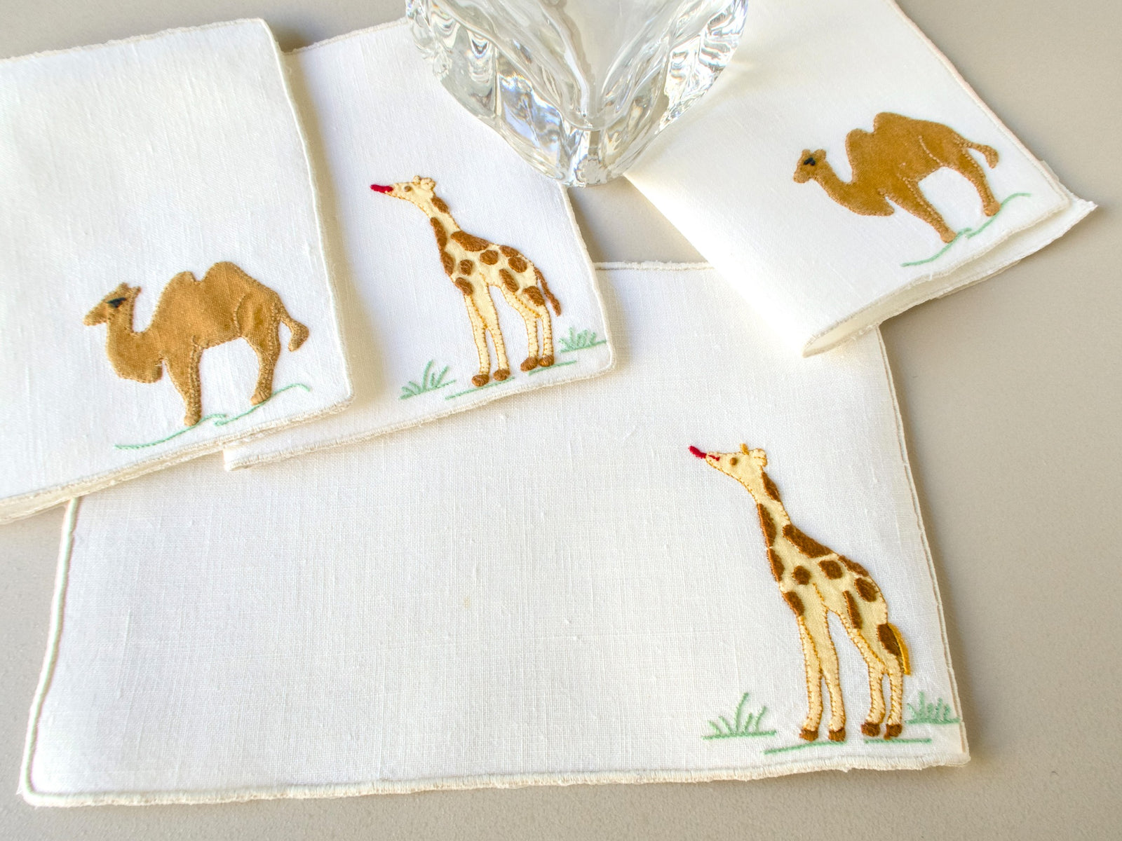 our vintage Madeira cocktail napkins showing camel and giraffe appliqué designs on off-white Irish linen