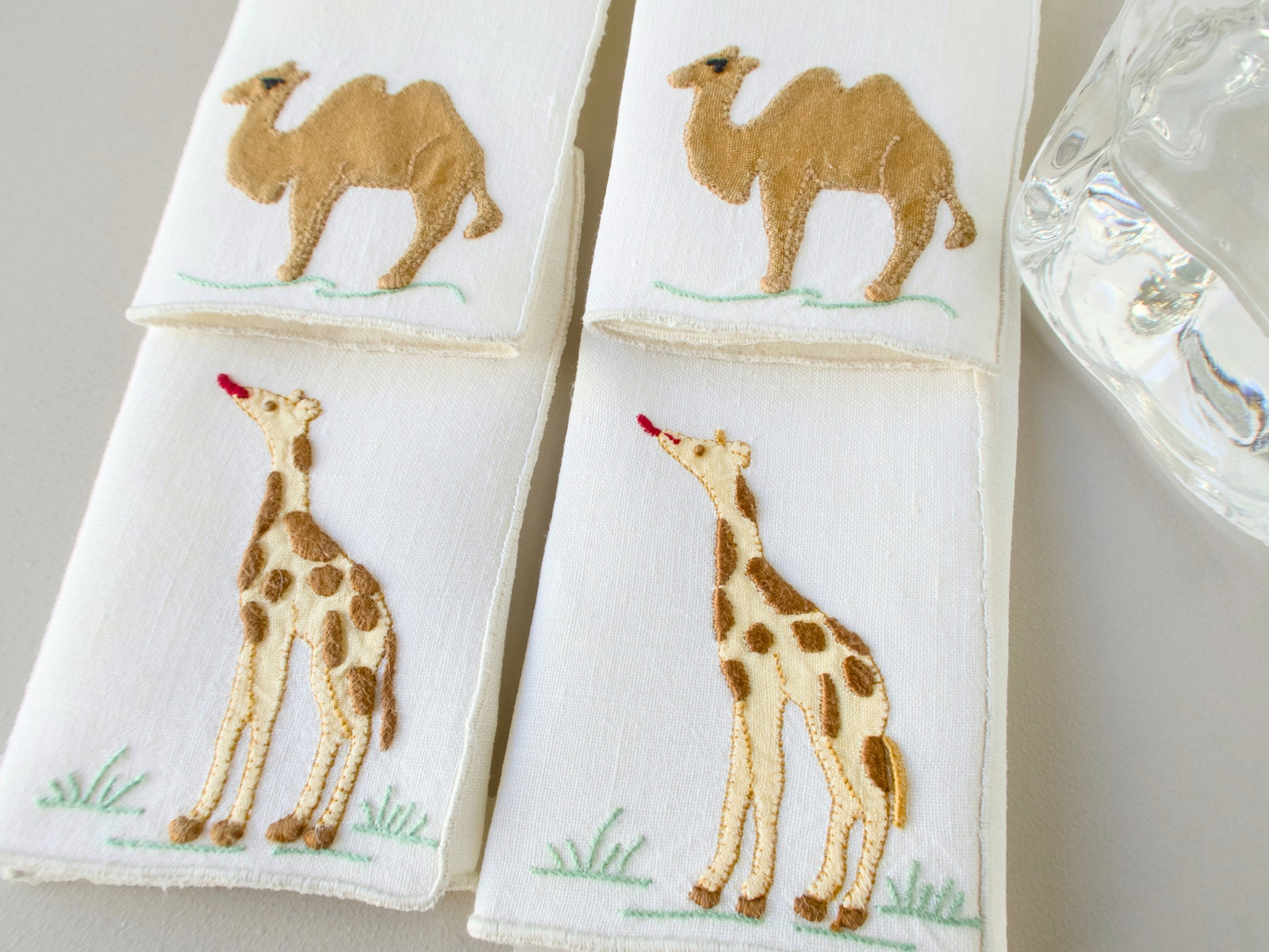 Close-up of vintage Madeira cocktail napkins showing camel and standing giraffe appliqué detail