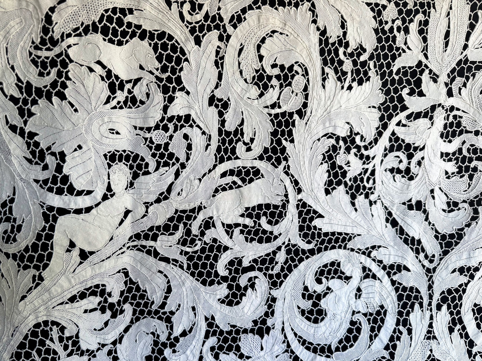 Reclining figure and running animals woven through elaborate floral scrollwork.