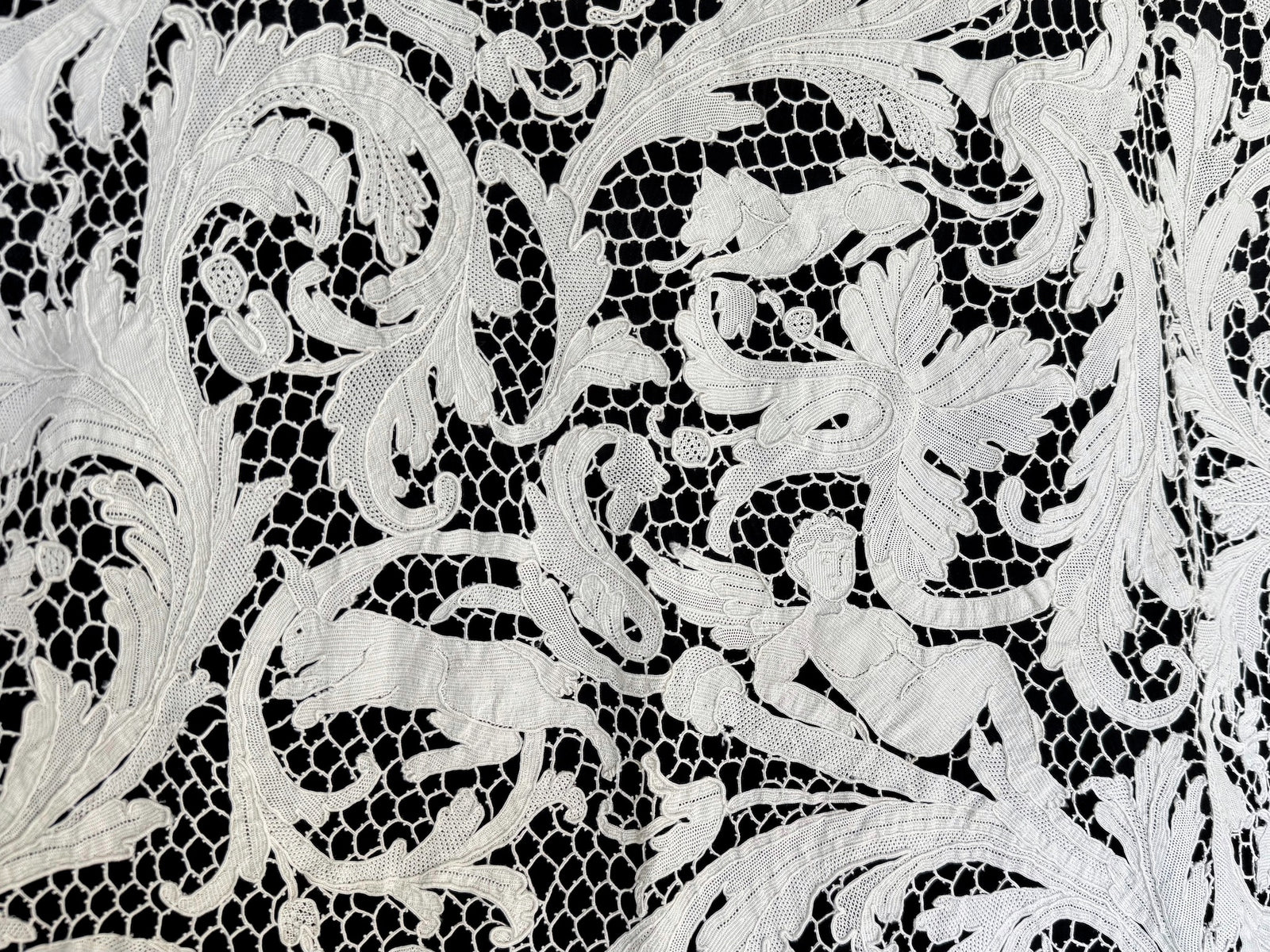 Reclining figure, hound and rabbit surrounded by scrolling leaves in the lace.
