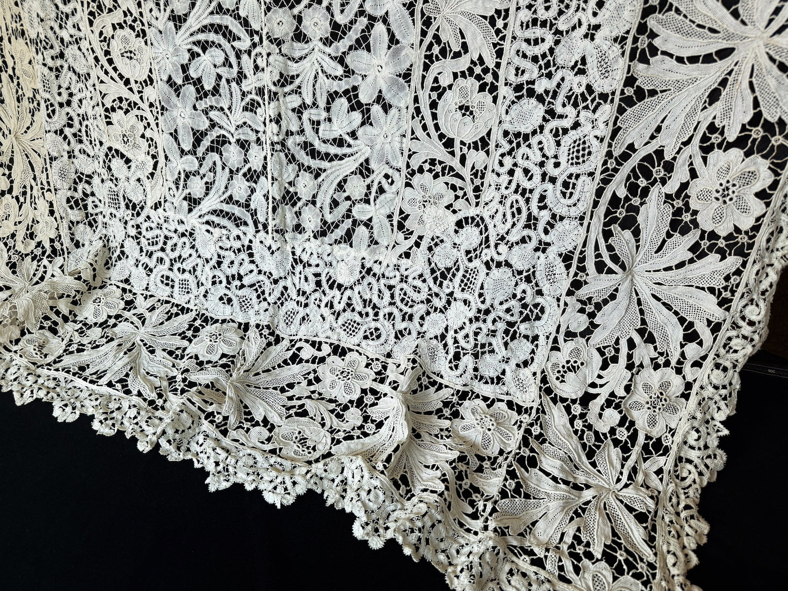 Opposite end of the antique French lace tablecloth with scrolling bobbin lace panels and a scalloped border, no cranes