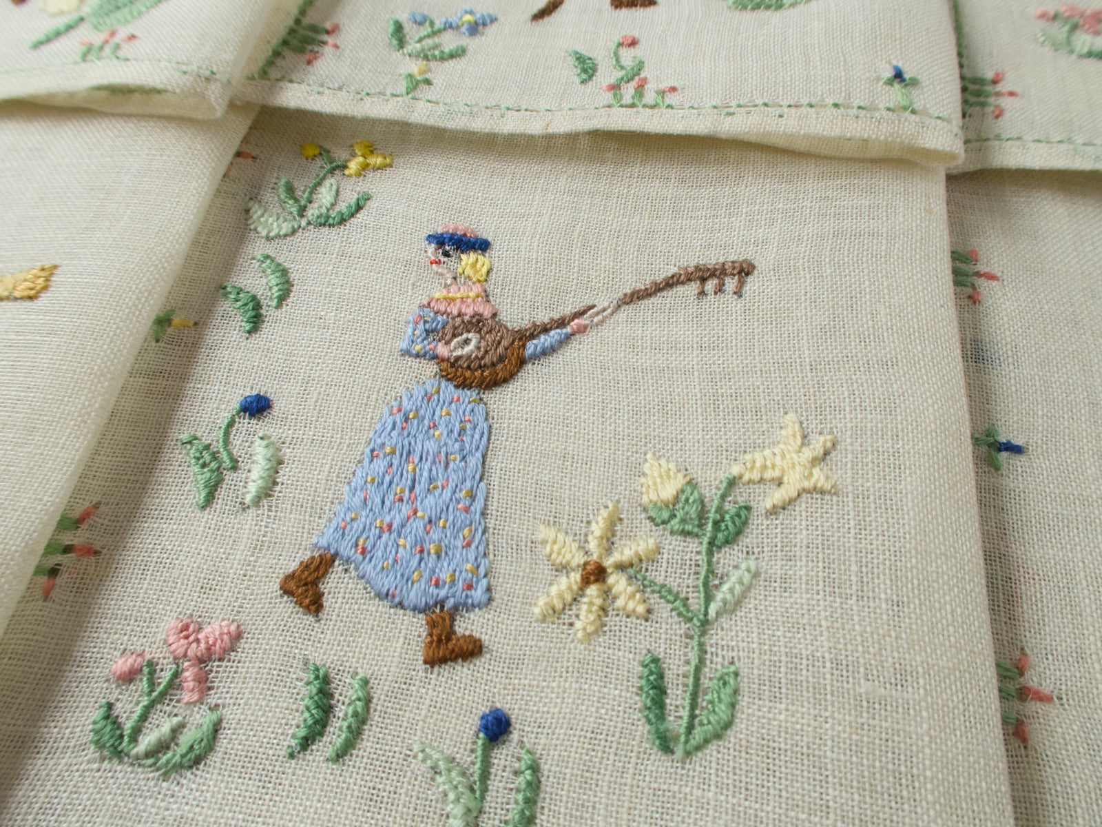 Close-up of a lute-playing musician on a cocktail napkin with stitched plants.