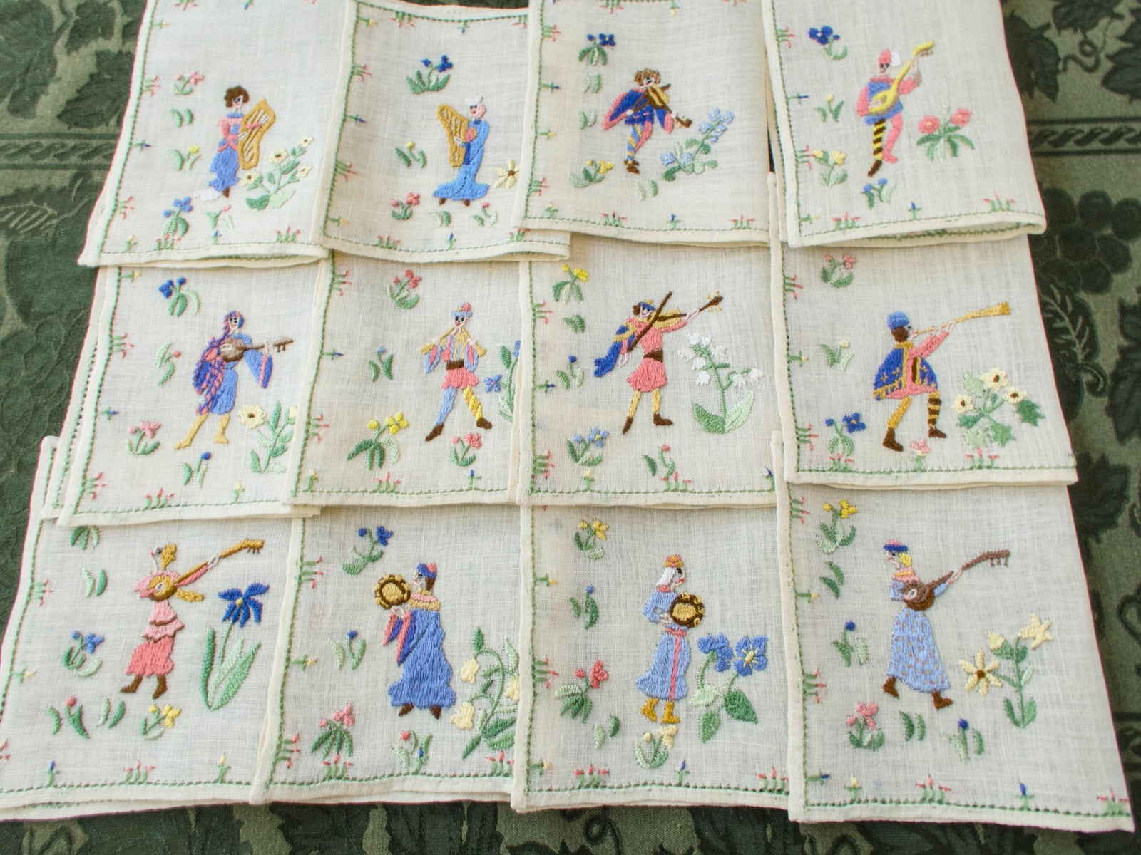 Full layout of all twelve Rapisardi medieval musician napkins arranged in a grid.