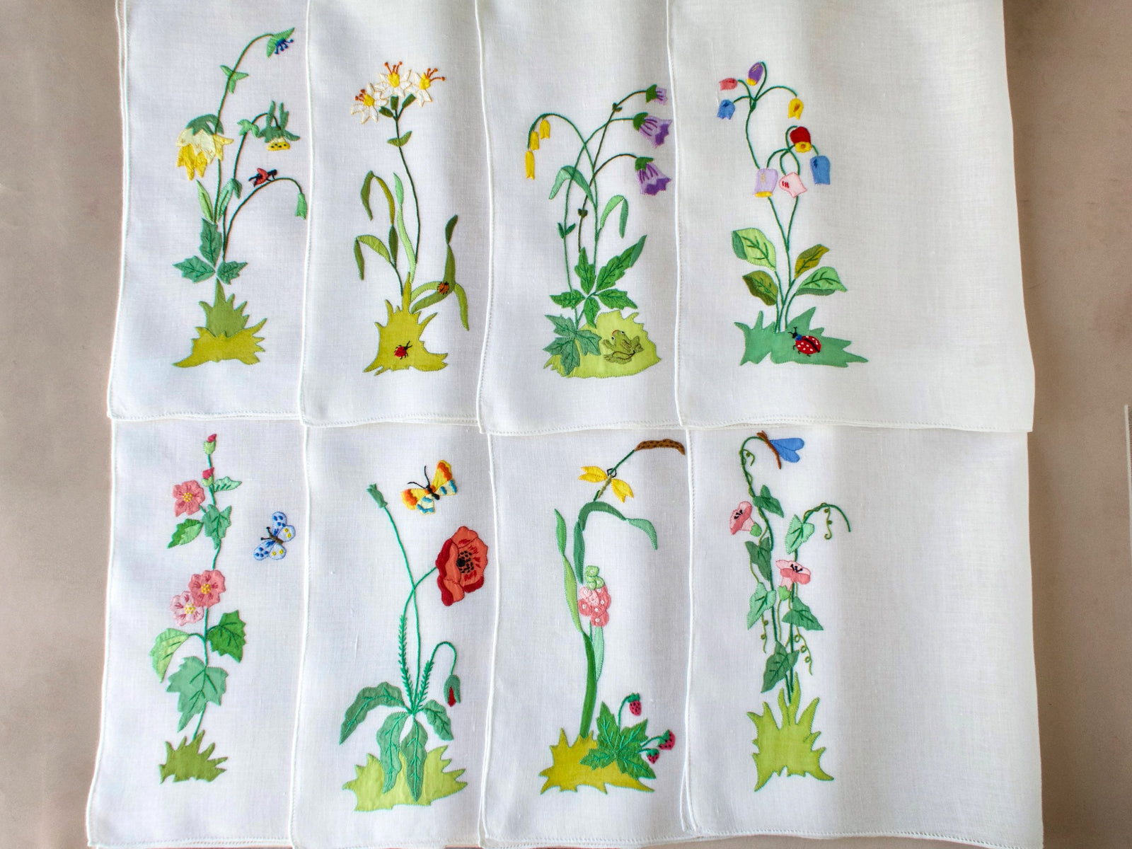 Set of vintage Italian embroidered linen placemats showing full collection of flower and insect designs displayed vertically