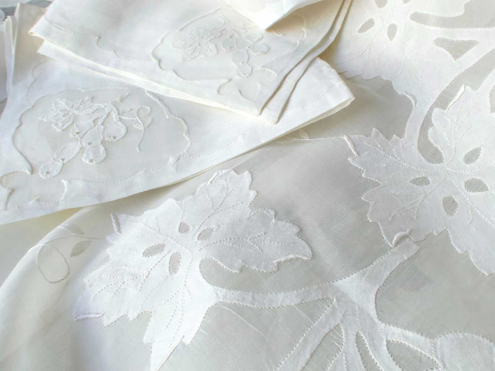 Detail of white embroidered grape leaves beside the matching napkins.