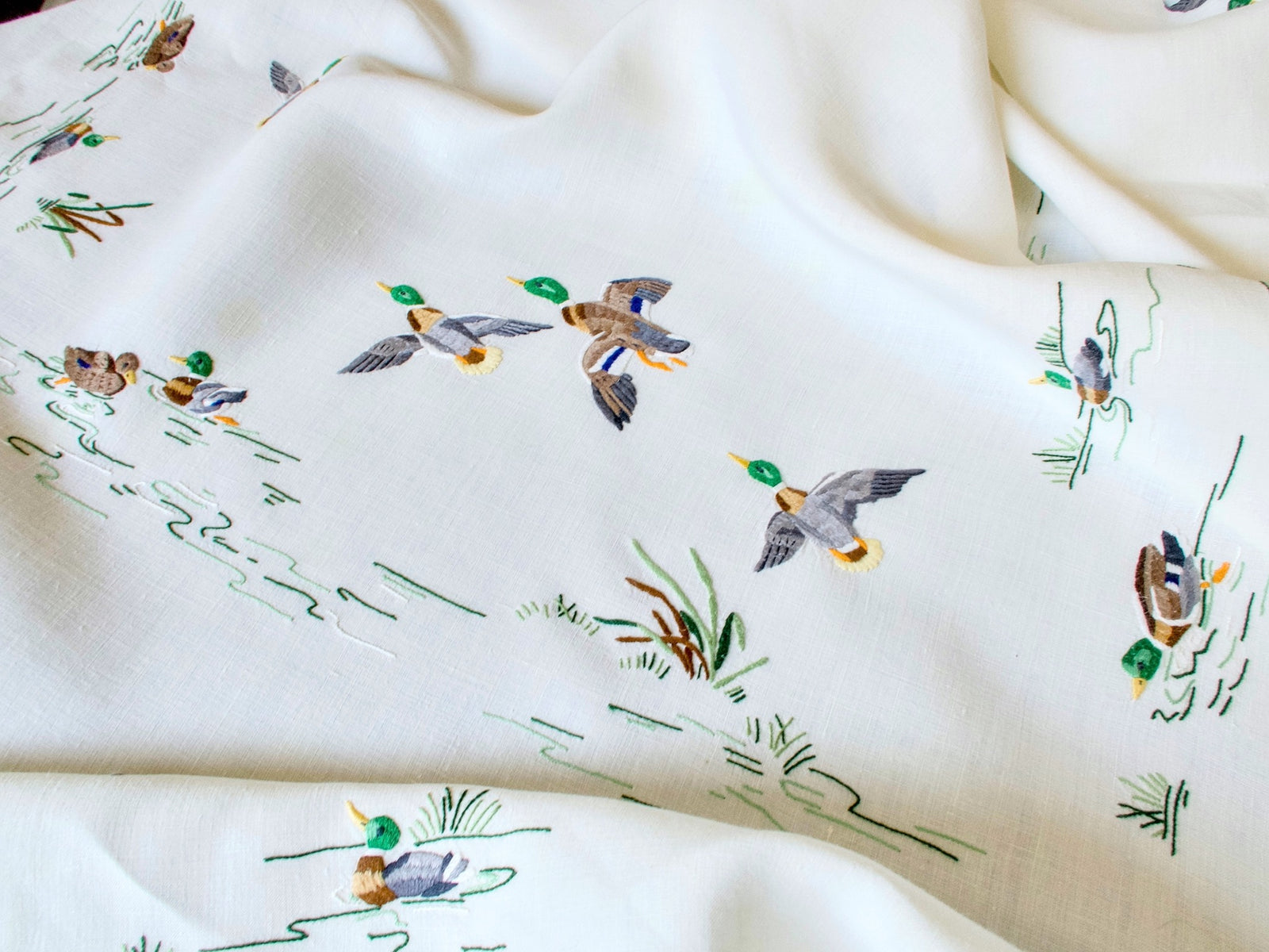 Detail of hand embroidered mallards in flight on vintage Madeira linen tablecloth