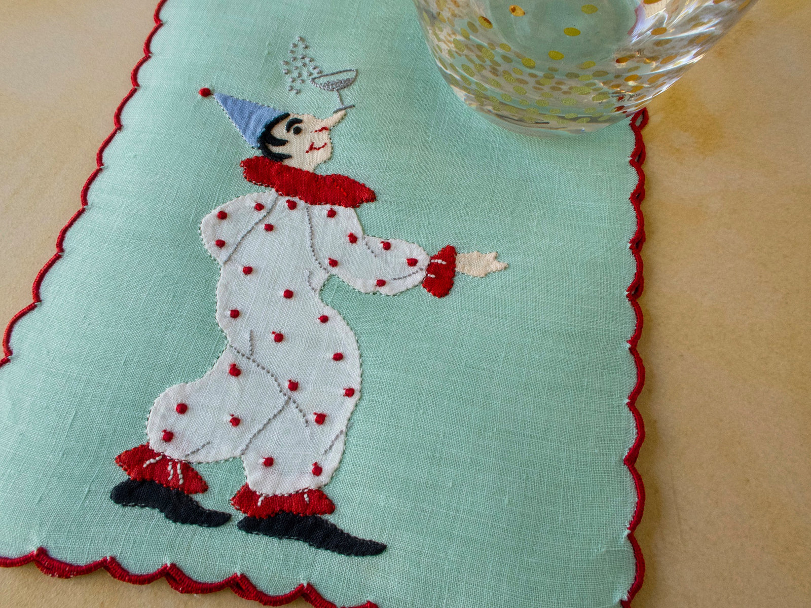 Clown balances a glass of champagne on his nose, embroidered vintage Madeira cocktail napkins