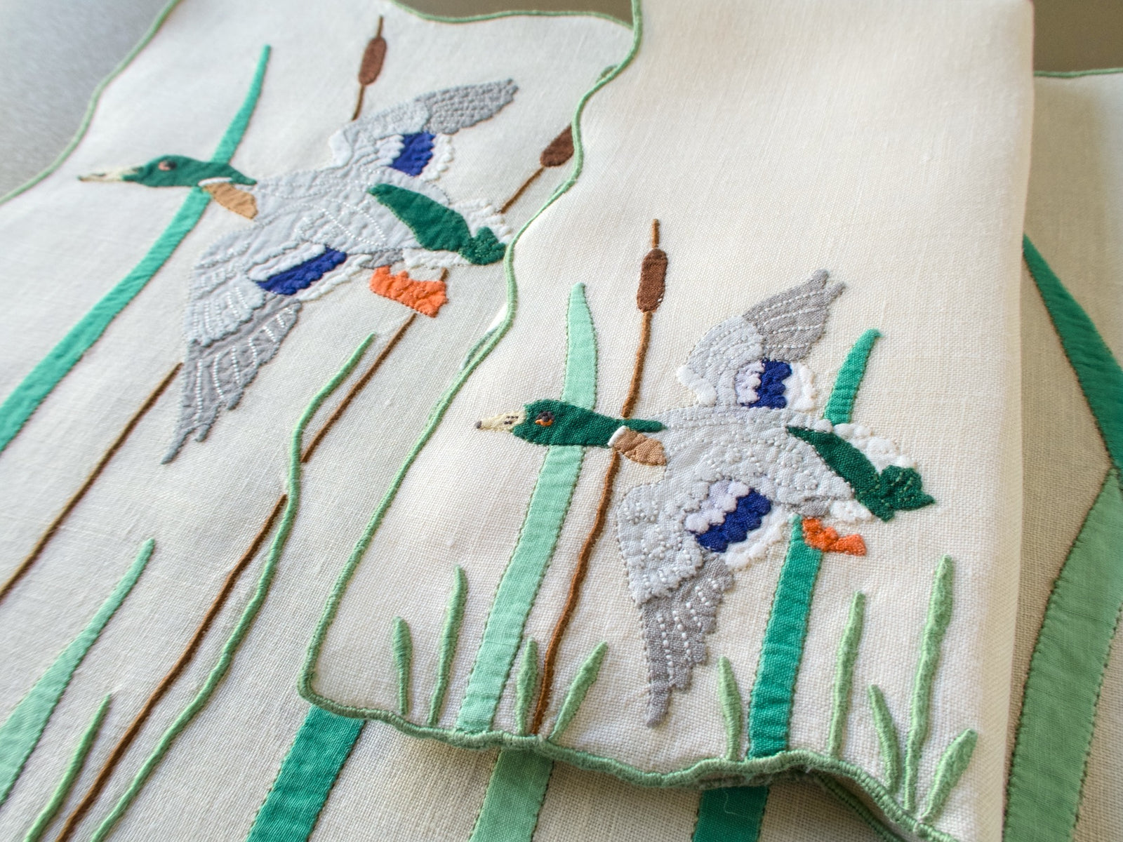 Vintage Madeira mallard placemat and folded napkin, each with a flying drake, cattails and green appliqué reeds