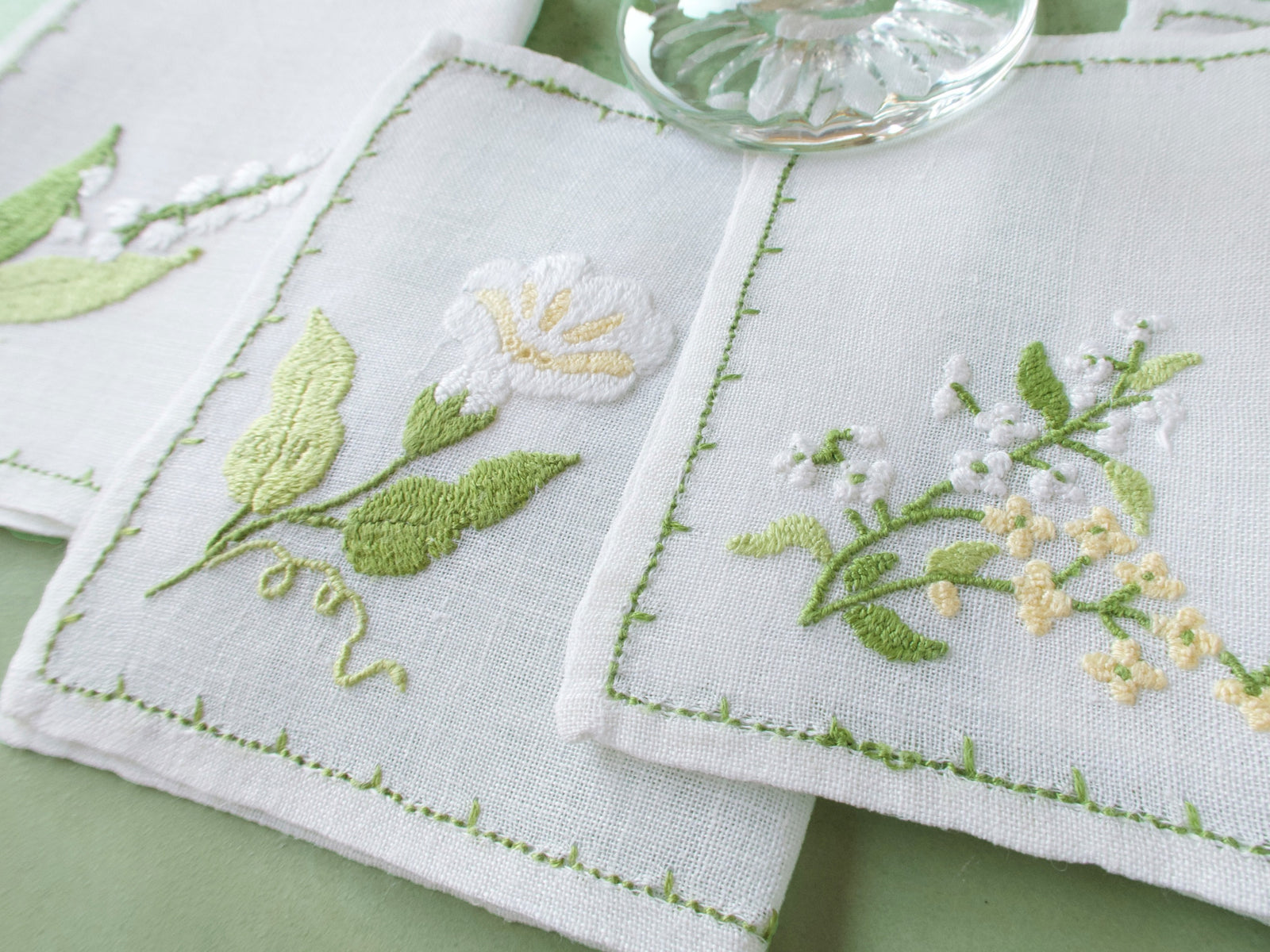 Vintage Baroness Rapisardi floral cocktail napkins in white linen with yellow and green hand embroidery, rectangular shape with hand-stitched border.