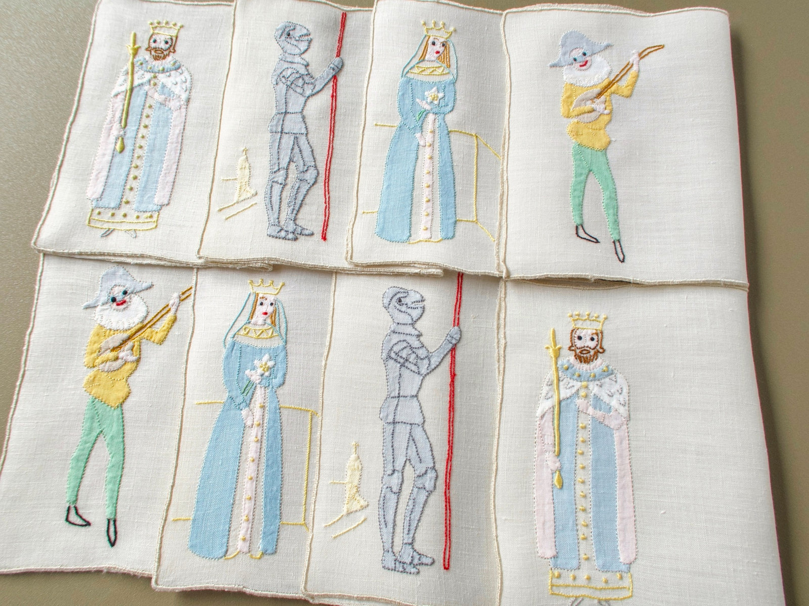 Eight vintage Madeira cocktail napkins laid out in two rows, each pair showing a king, jack, queen or lute-playing joker