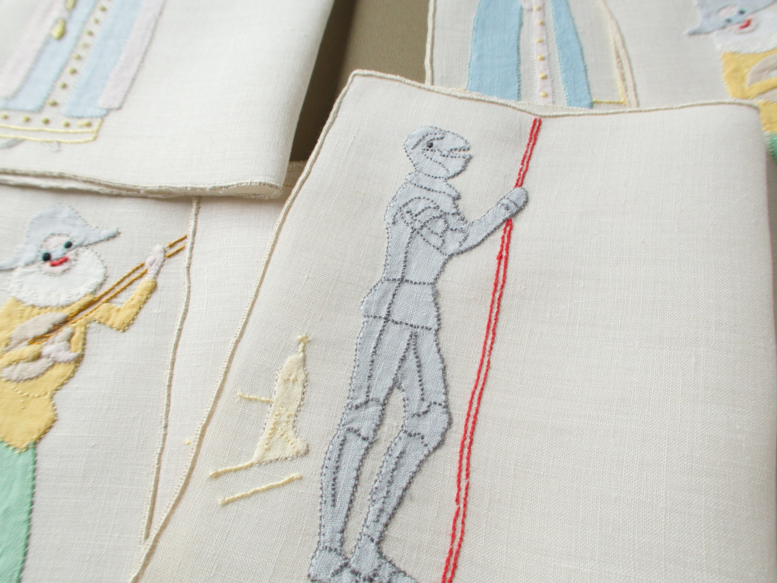 Close view of an appliqué jack in armor with a red lance on a vintage Madeira cocktail napkin