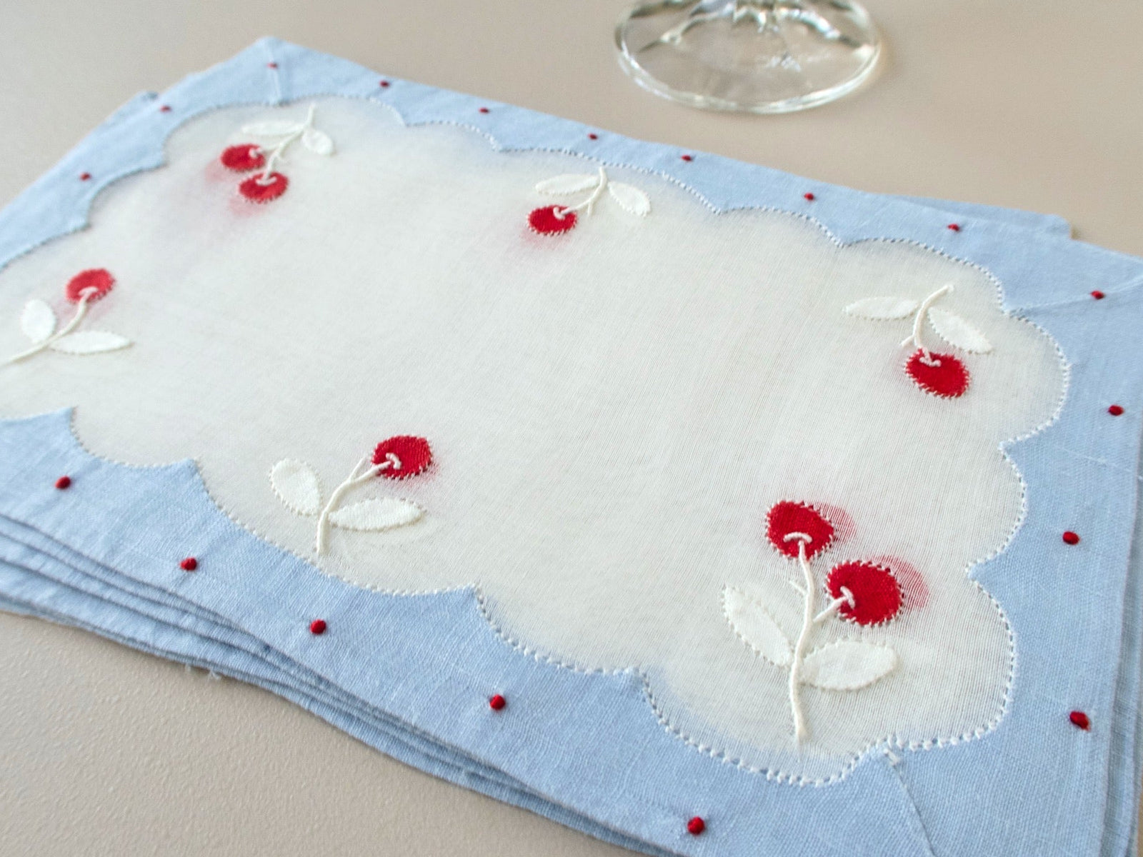 Stack of vintage Madeira cocktail napkins with cherry appliqué, stitched leaves and a scalloped organdy center
