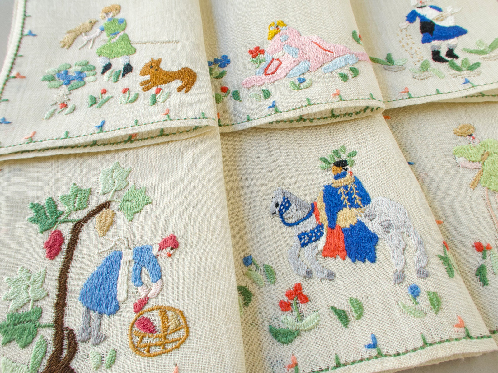 Vintage Baroness Rapisardi Months of the Year cocktail napkins hand embroidered in punto stuoia with a falconer, a sower, a grape picker and a rider on a gray horse from medieval Labors of the Months imagery