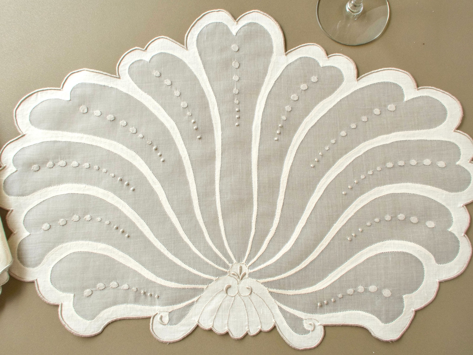 Overhead view of a full vintage Madeira fan-shaped placemat with linen appliqué petals on organdy and rows of hand embroidered dots