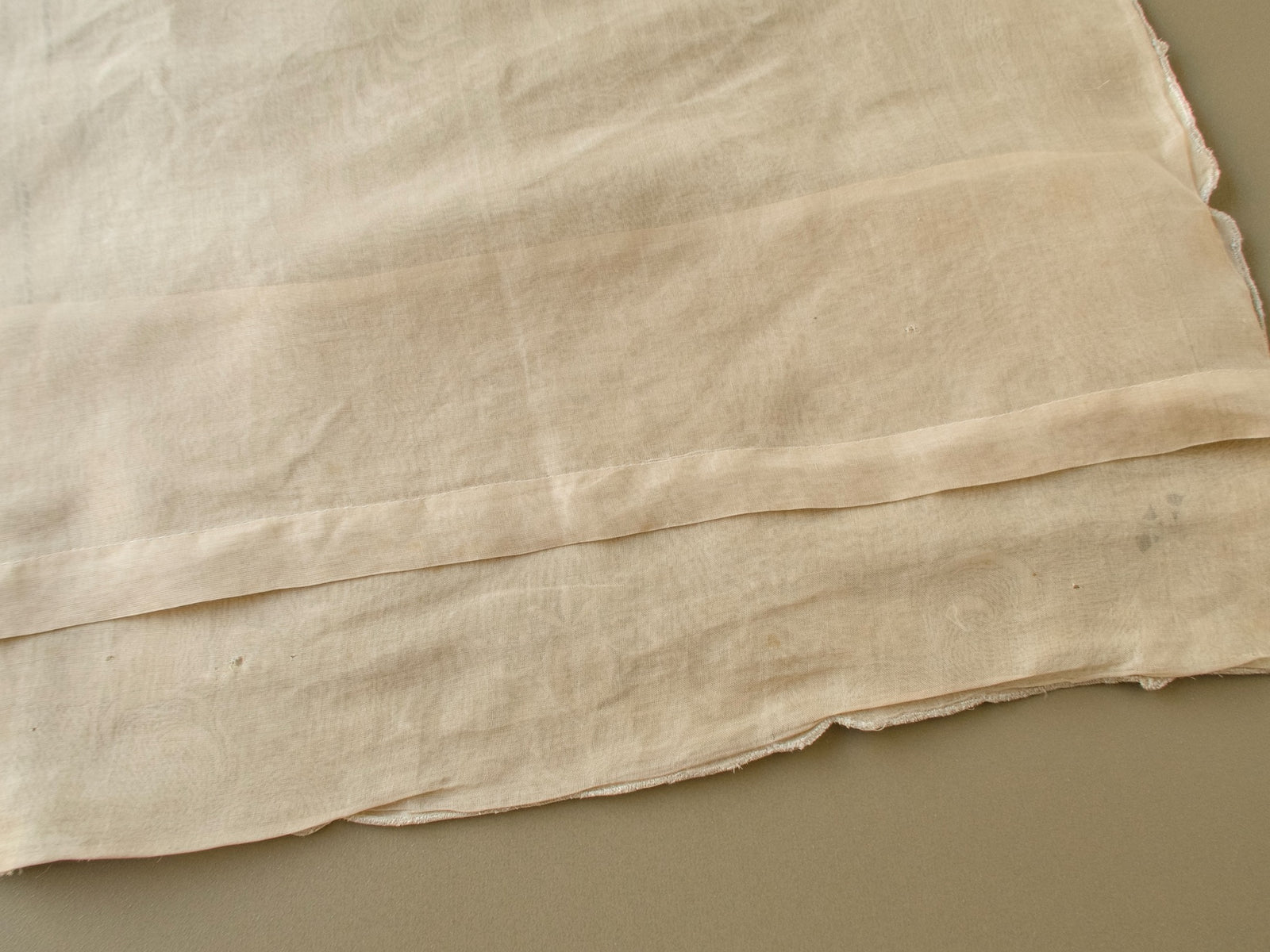 Back of a vintage Marghab organdy pillow cover showing a couple of small holes in the organdy