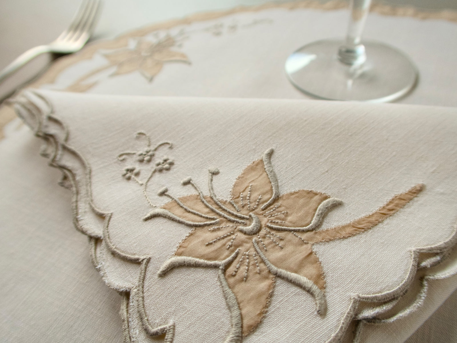 Close-up detail of vintage Madeira lily showing dimensional organdy appliqué petals and stamens on ecru linen