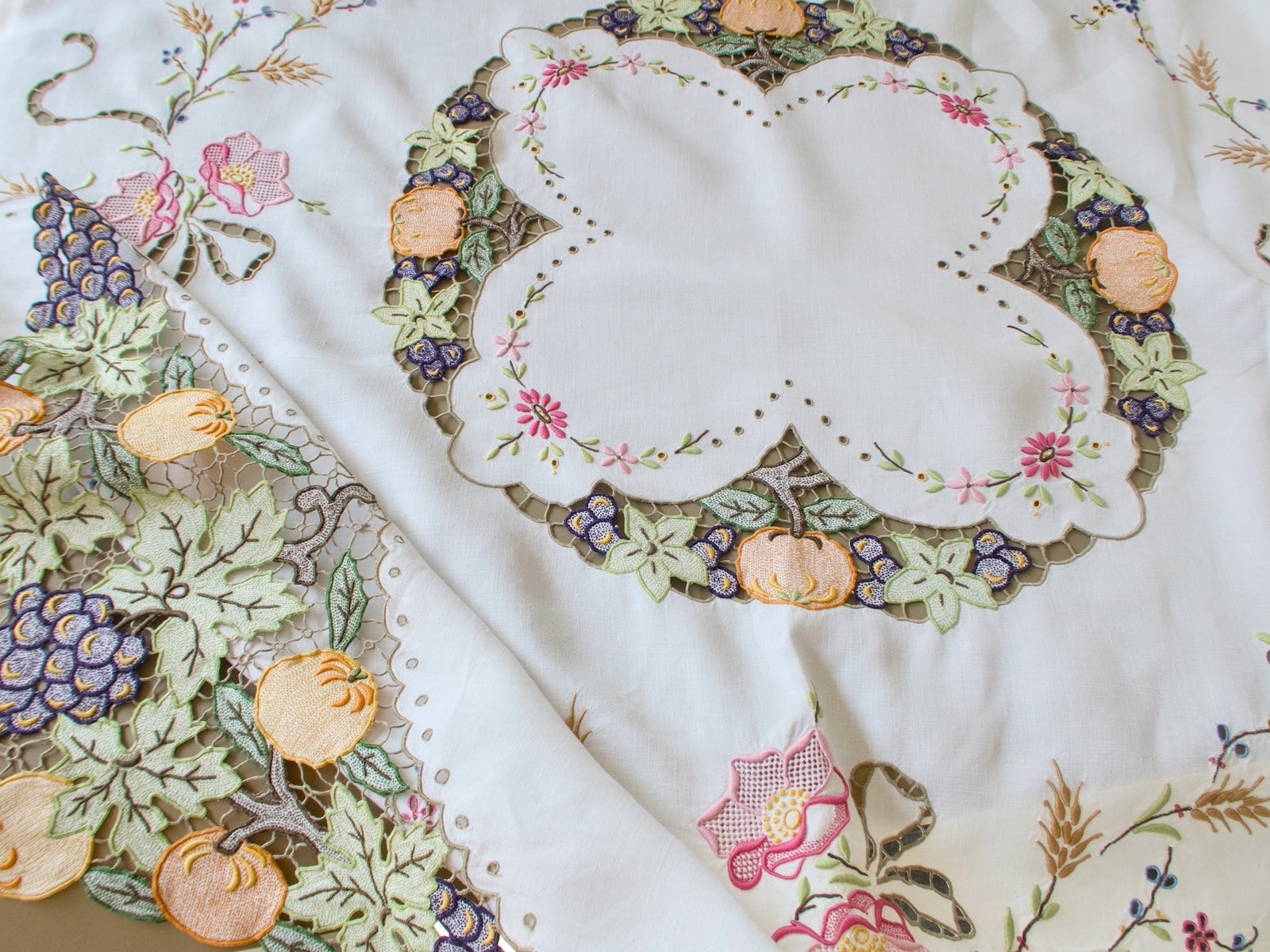 Scalloped center wreath of a vintage Madeira tablecloth ringed with cutwork pumpkins, grapes and vine leaves and embroidered flowers