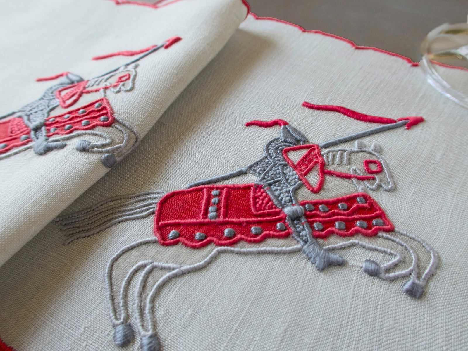 Vintage Marghab Knight pattern cocktail napkins, red embroidery on oyster-colored linen showing knight on horseback, handmade in Madeira.