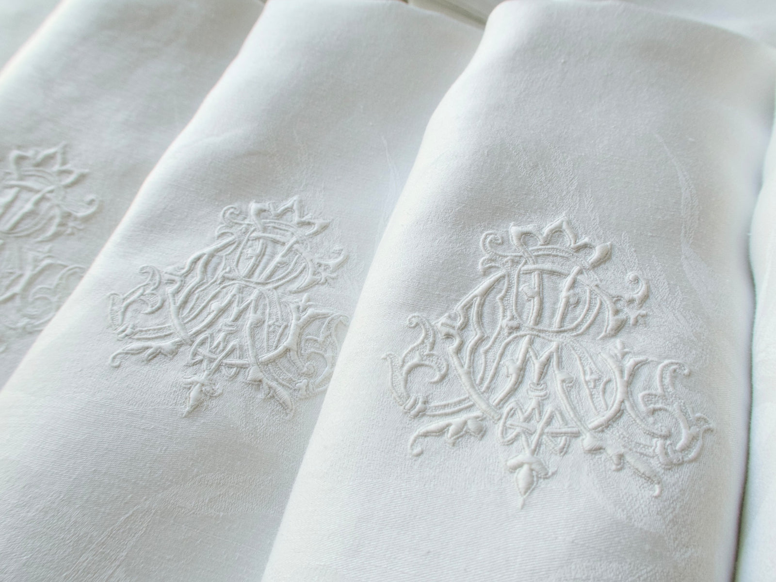 Two antique damask linen napkins folded to show a hand embroidered triple monogram ACR