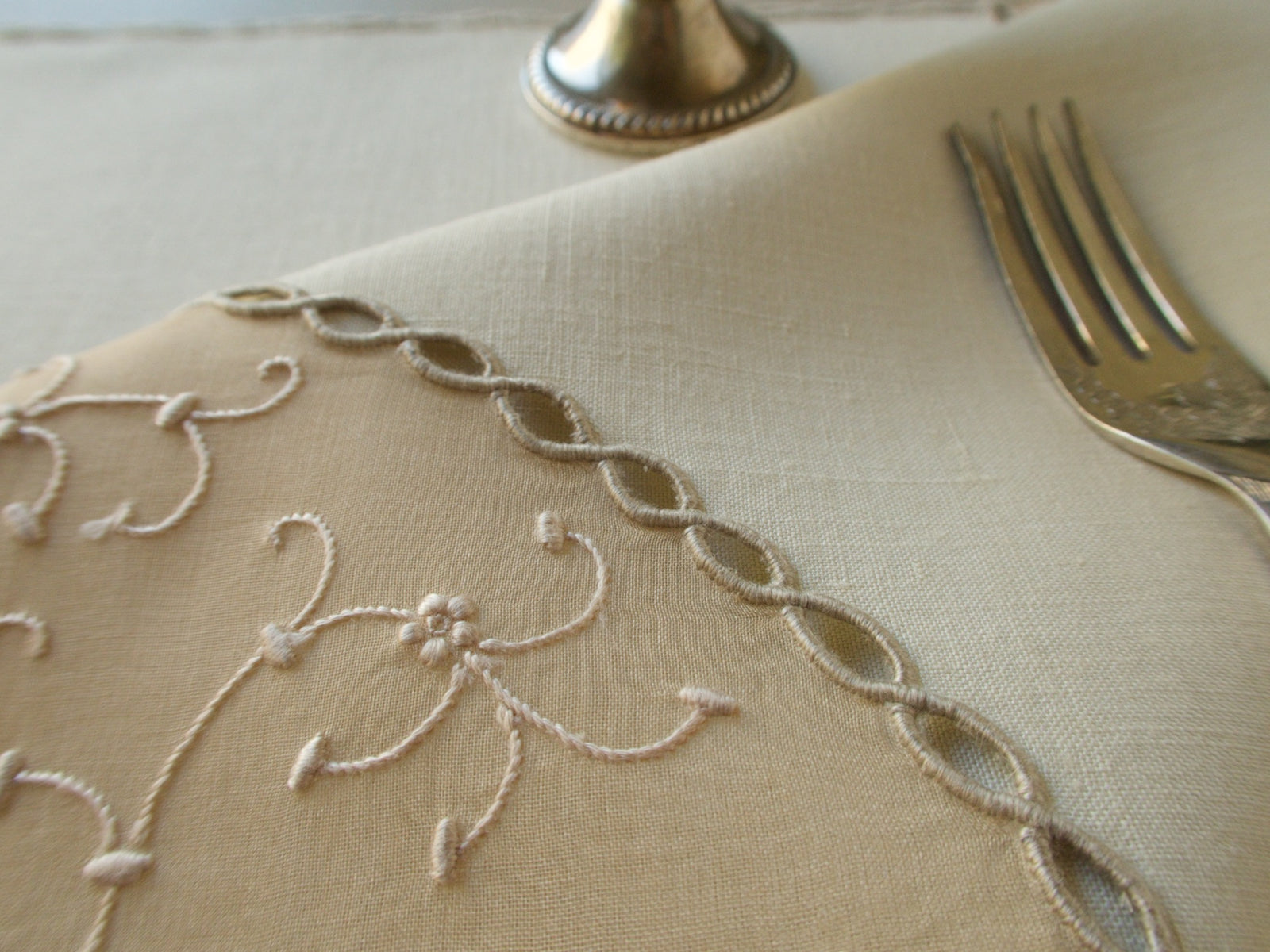 Detail from Marghab's “Open Lacing” placemat and napkin set, hand embroidered in Madeira on fine linen and organdy with tone-on-tone floral motifs and delicate caseado bastido edges.