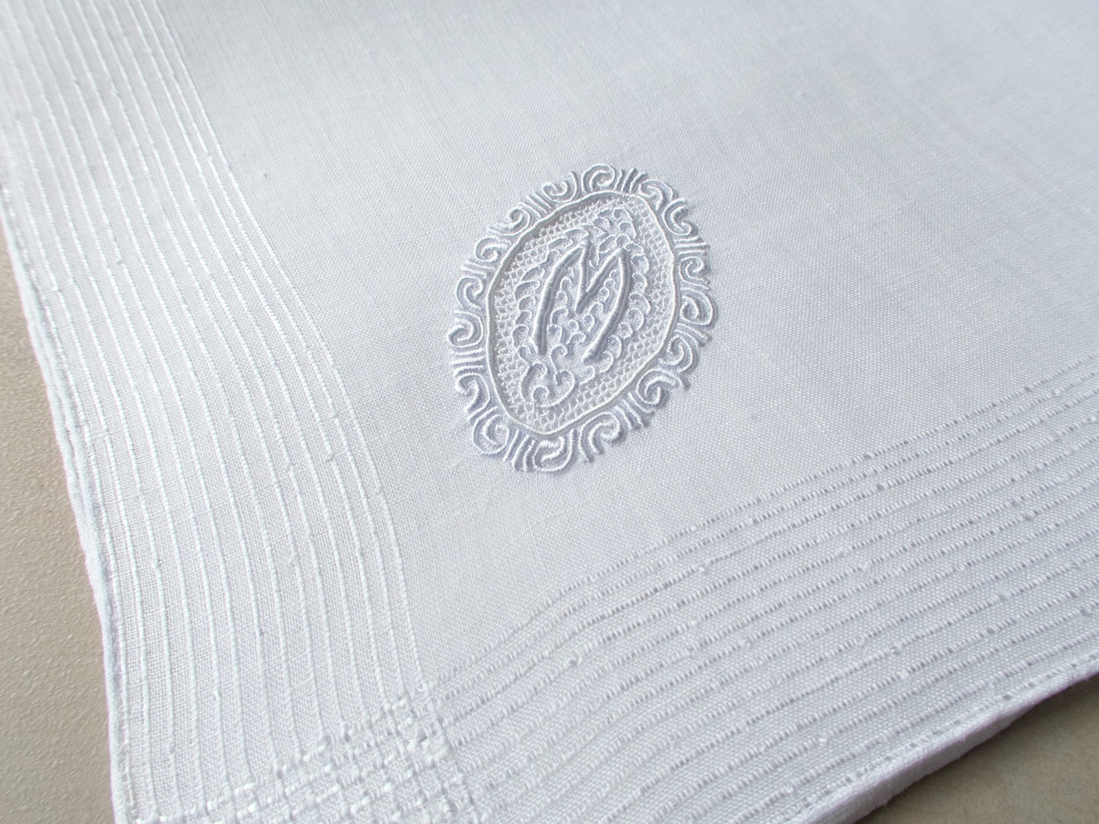 Vintage Marghab handkerchief featuring an “M” monogram in the “Oval Initial” pattern, hand embroidered in white on fine linen. Elegant and beautifully made.