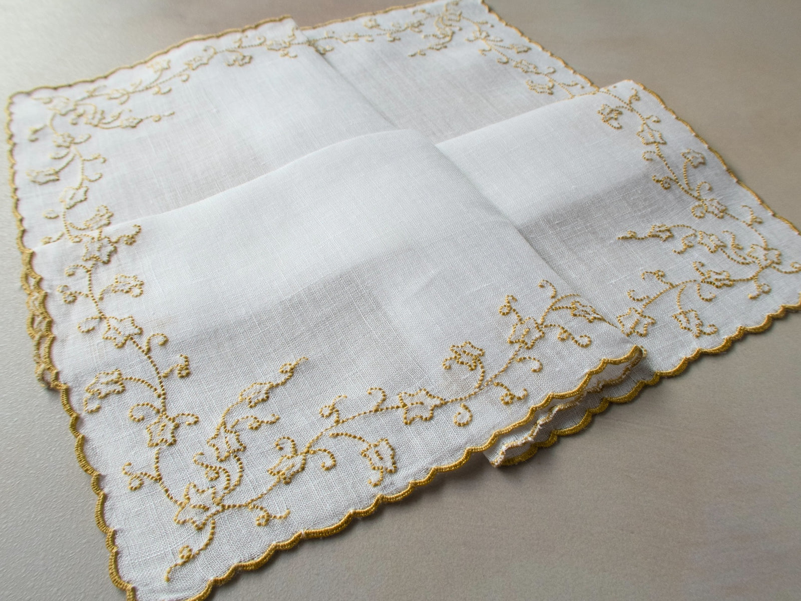 Vintage Marghab “English Ivy” handkerchief, hand embroidered in gold on fine white linen, featuring flowing vine motifs along the scalloped edge.