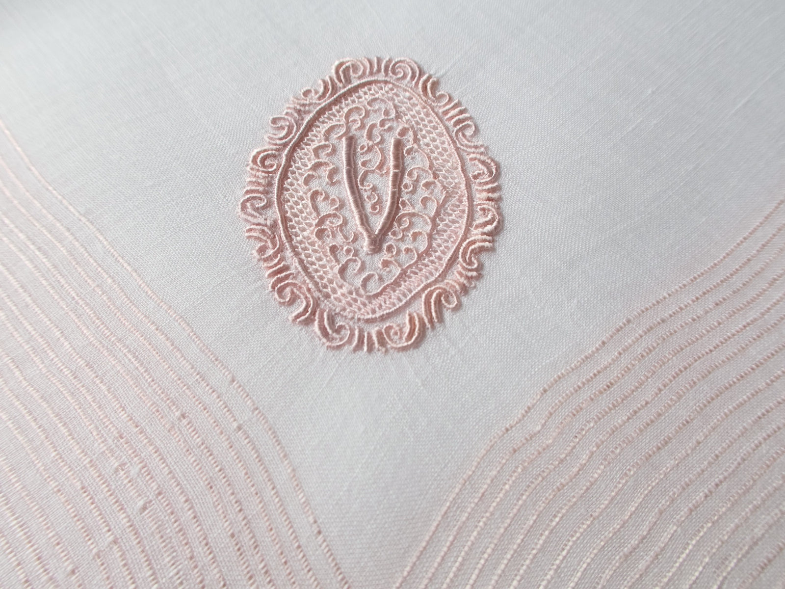 Vintage Marghab handkerchief featuring a “V” monogram in the “Oval Initial” pattern, worked in soft pink embroidery on fine linen. Hand embroidered in Madeira.