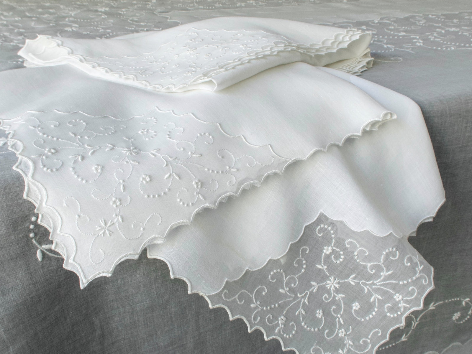 Close-up of vintage Marghab white embroidered linen napkins draped over a sheer organdy tablecloth, hand embroidered in Madeira