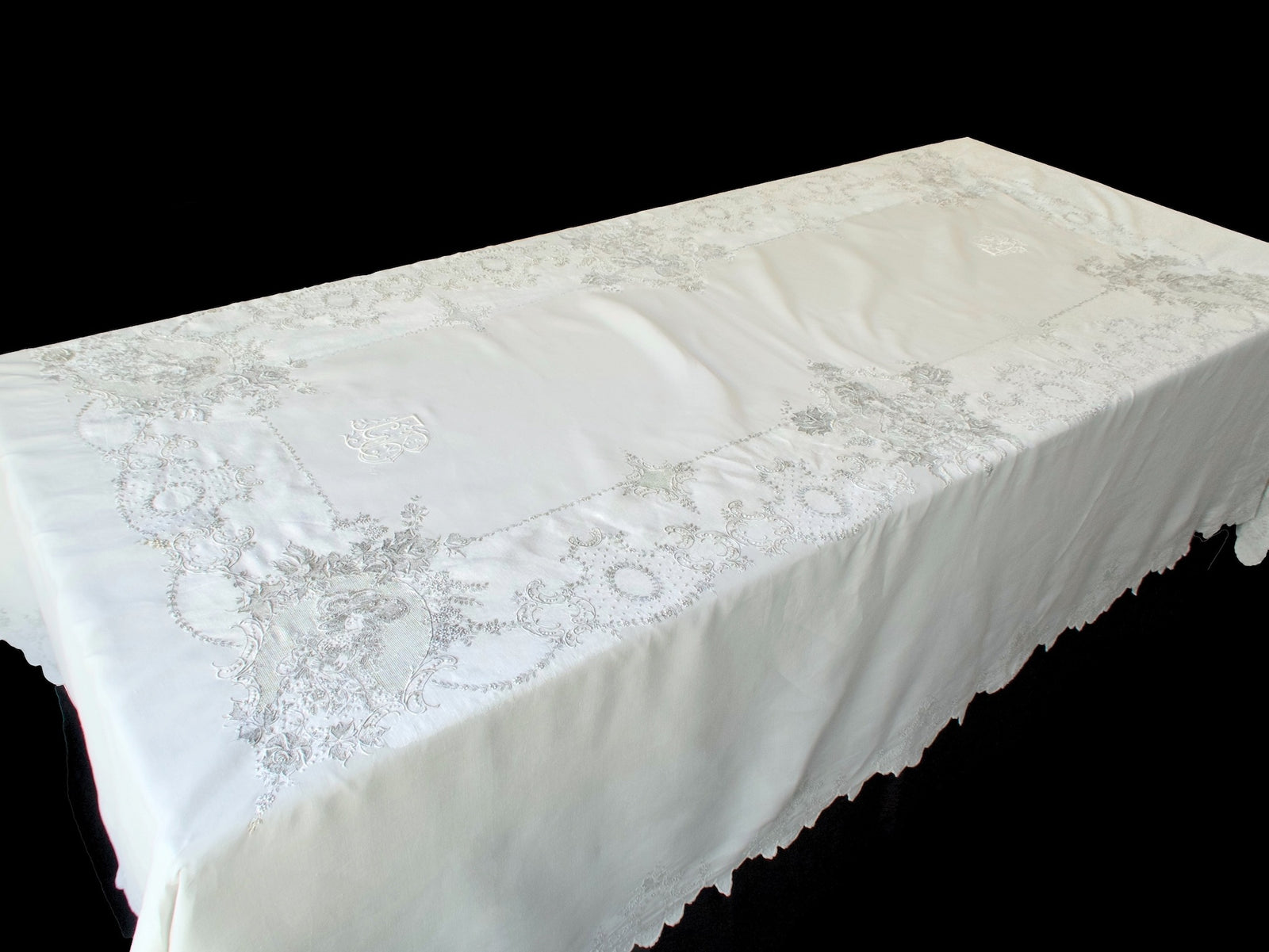 Full view of Swiss Appenzell embroidered tablecloth with figural design and scrolling floral borders