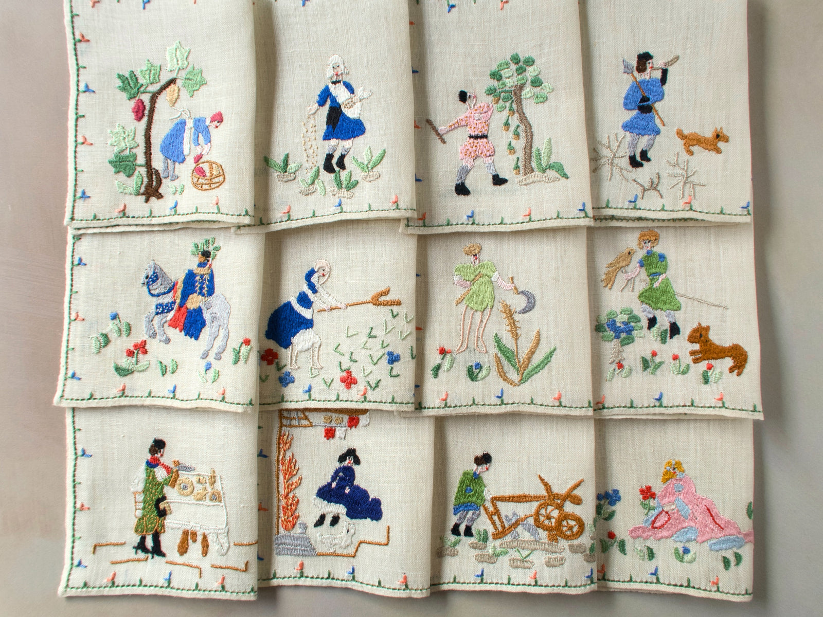 Full set of twelve Months of the Year Rapisardi napkins arranged in three rows, each showing a different monthly scene with figures and flowers.