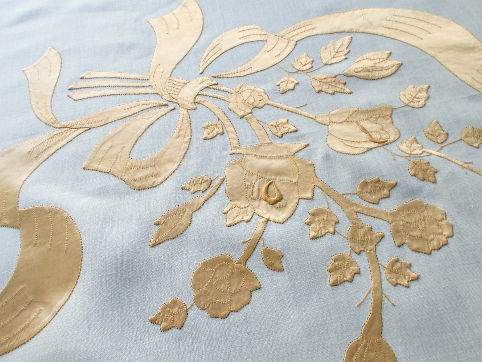 Detail of flowing satin ribbon embroidery on vintage Madeira tablecloth