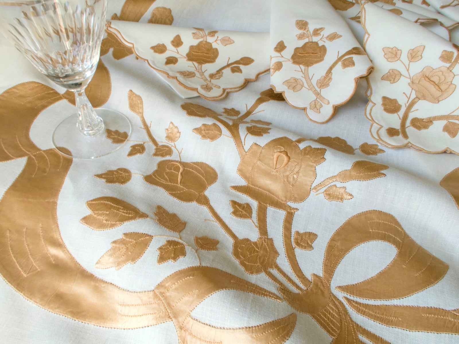 Detail of vintage Madeira linen tablecloth with satin appliqué roses and ribbon design
