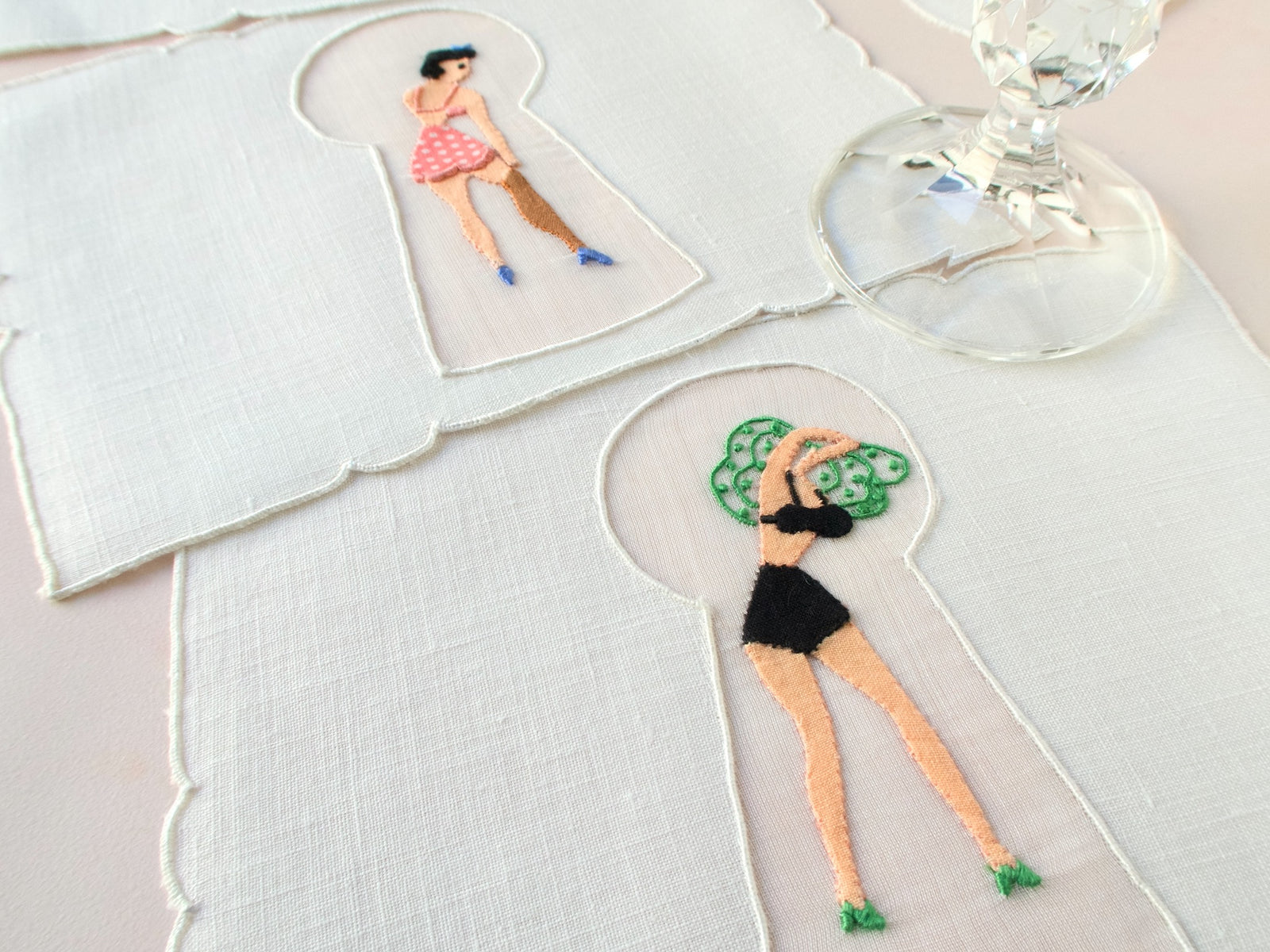 Detail of keyhole embroidery showing woman pulling off her green dress, vintage Madeira linen cocktail napkin.