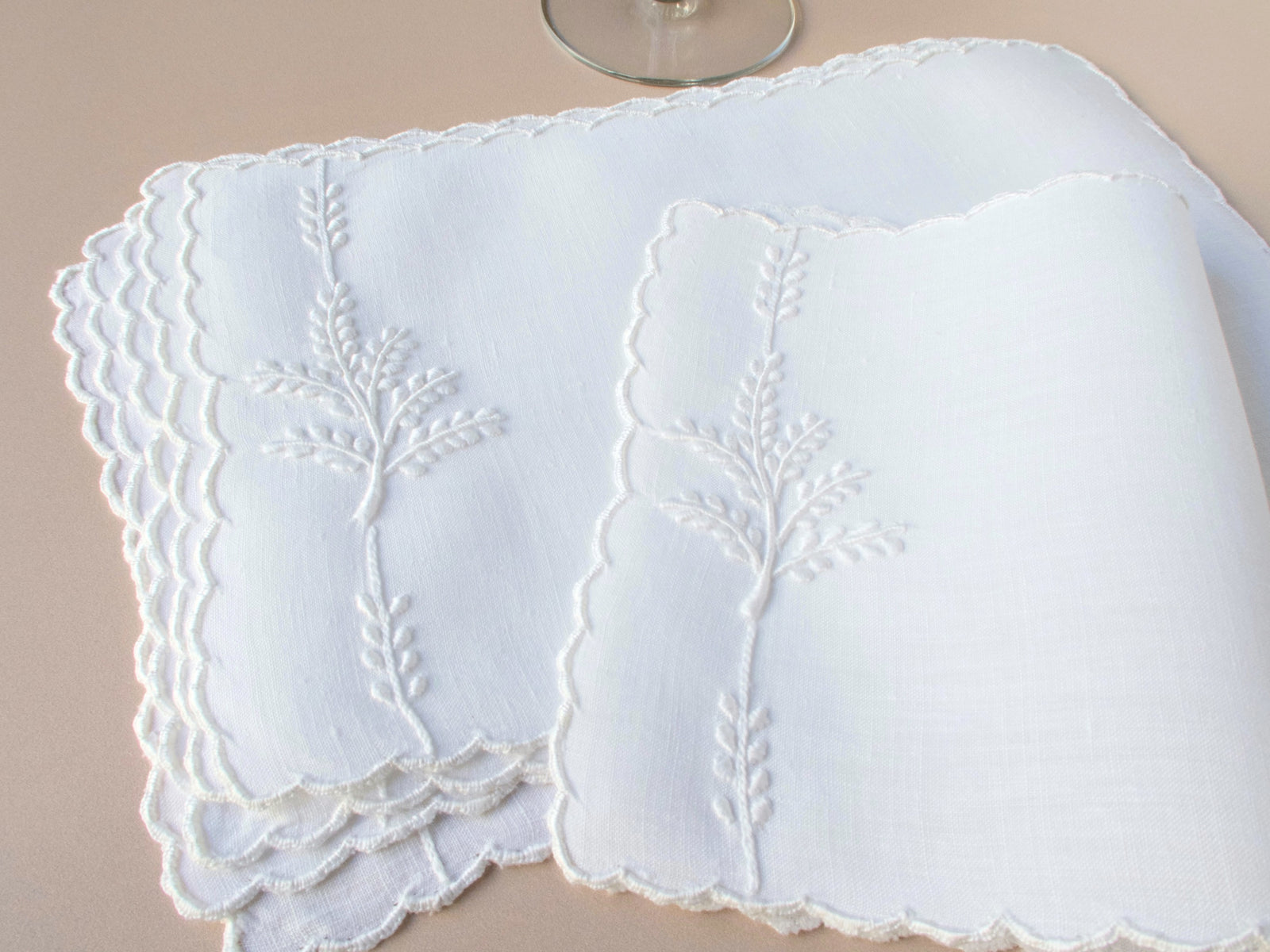 Vintage Madeira cocktail napkins with whitework leaf embroidery and scalloped edges, layered in soft natural light.