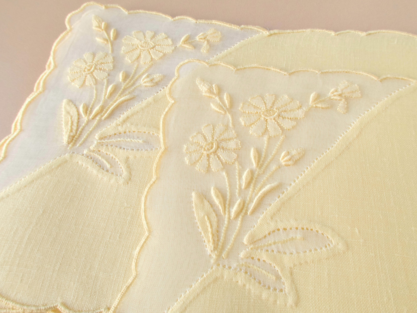 Close up of hand embroidered floral motif on vintage Madeira linen cocktail napkin, scalloped organdy window detail