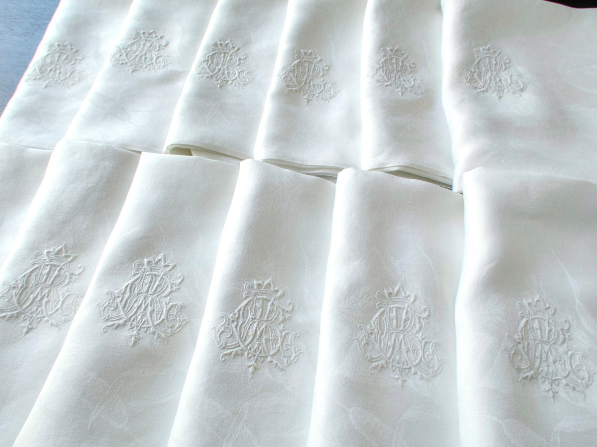 Row of antique damask linen napkins fanned out to show the hand embroidered triple monogram ACR on each