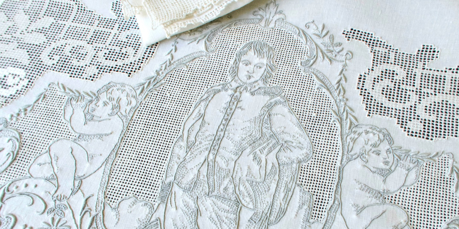 vintage decorative embroidered tablecloth with intricate patterns and a the famous Blue Boy, along with cherubs