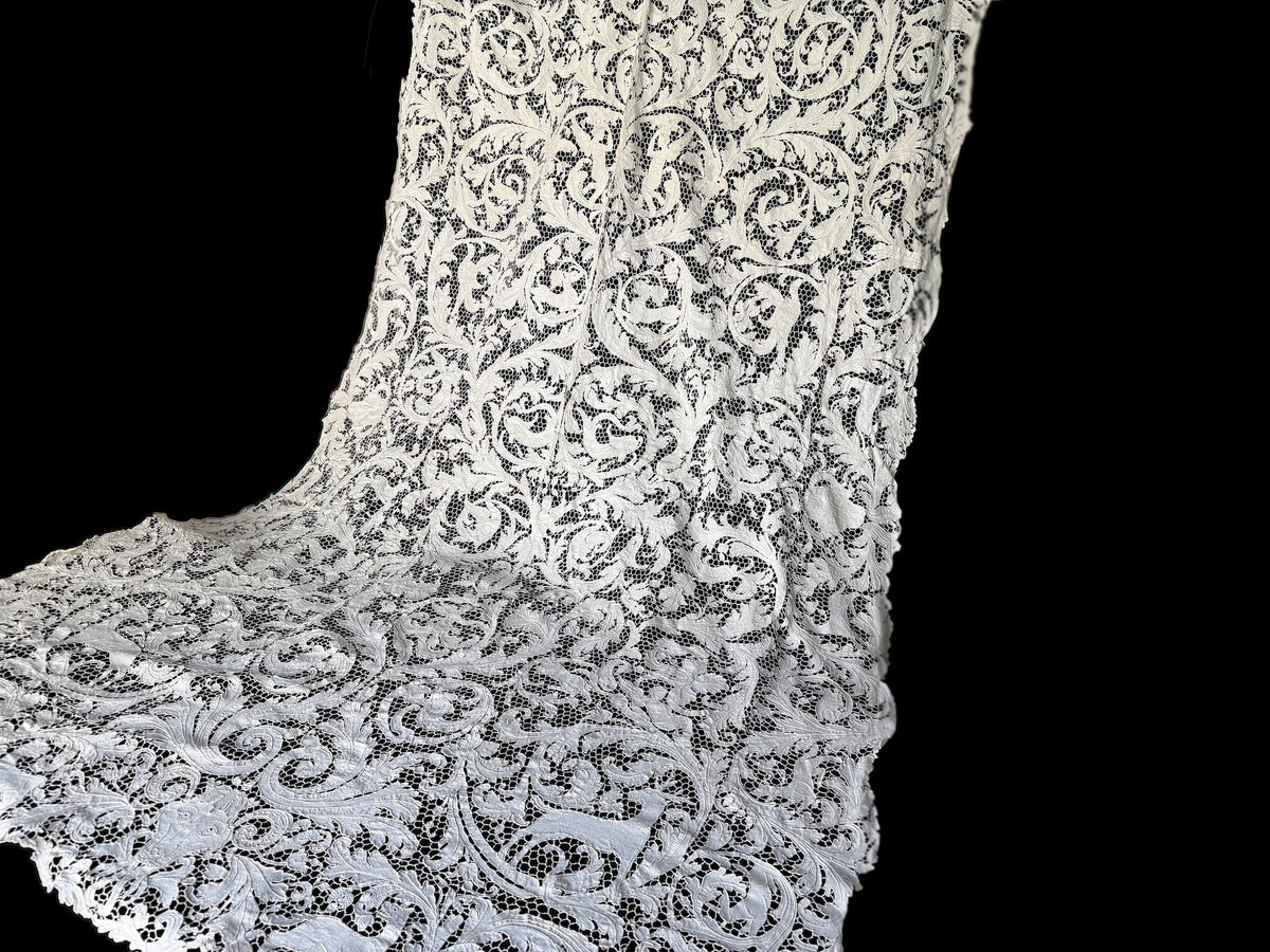 Creamy white figural lace tablecloth draped against a dark background.