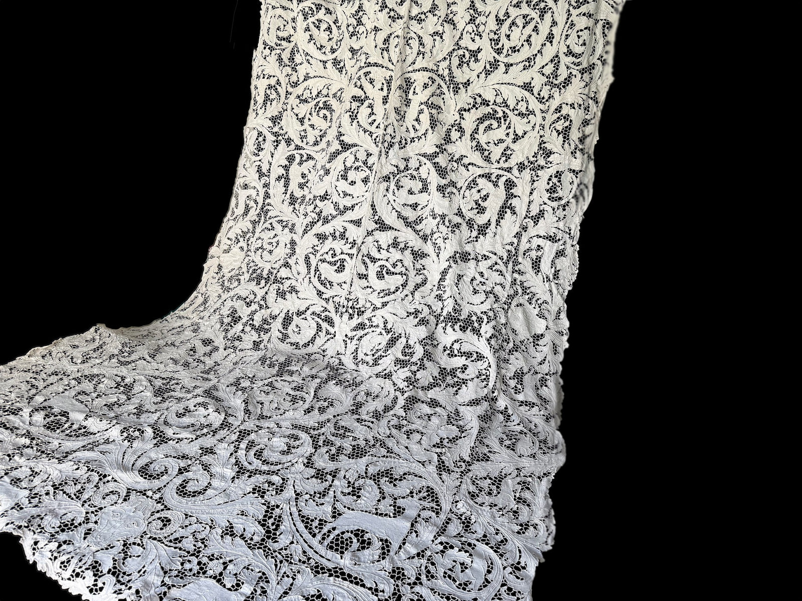 Creamy white figural lace tablecloth draped against a dark background.